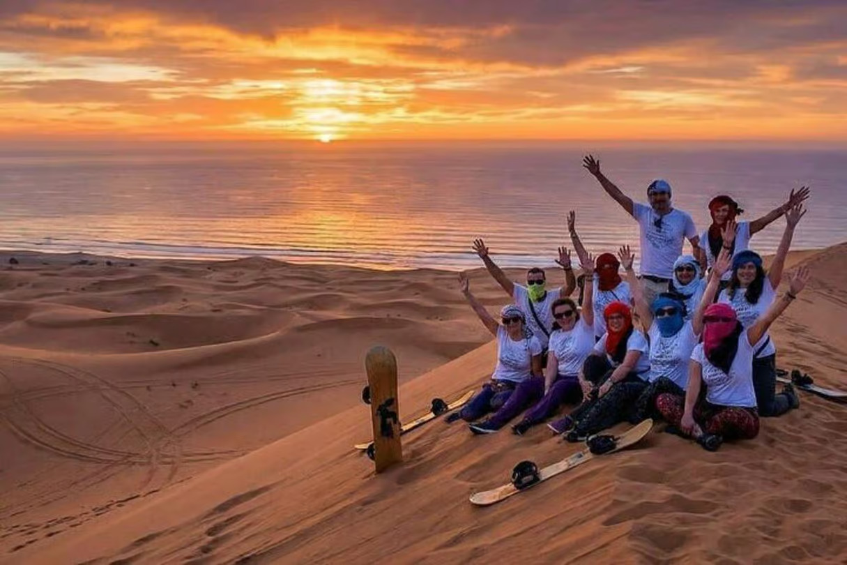 Group sandboarding on the dunes at sunset near Timlaline